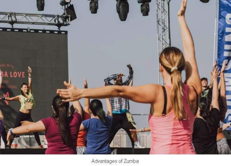 Advantages of Zumba,A group of people with raised arms enjoying a high-energy outdoor Zumba dance session.