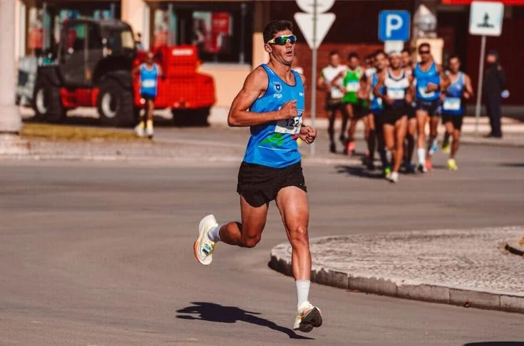  Can Running Increase Muscle Mass,A group of marathon runners racing down a city street, with a runner in a blue jersey in the foreground